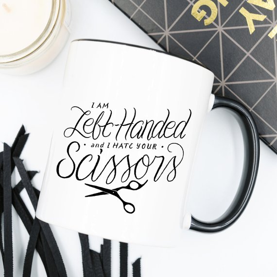 A humorous coffee mug featuring the phrase 'I Am Left-Handed And I Hate Your Scissors', designed for left-handed users.