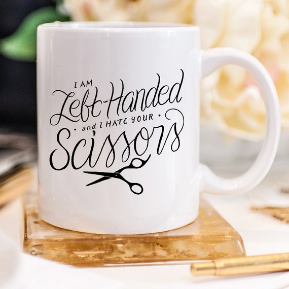 A humorous coffee mug featuring the phrase 'I Am Left-Handed And I Hate Your Scissors', designed for left-handed users.