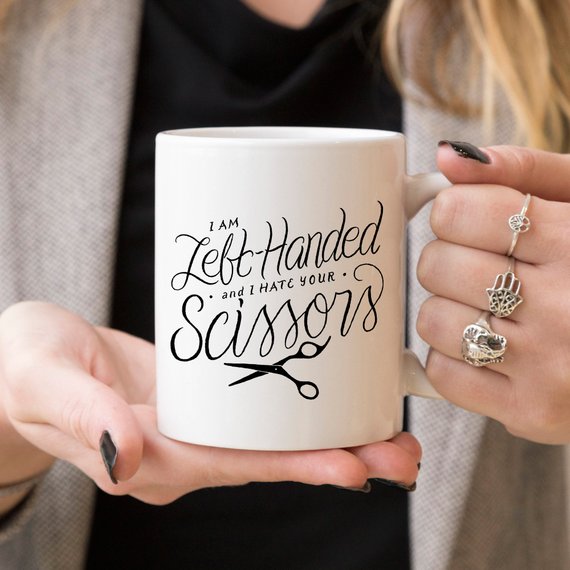 A humorous coffee mug featuring the phrase 'I Am Left-Handed And I Hate Your Scissors', designed for left-handed users.