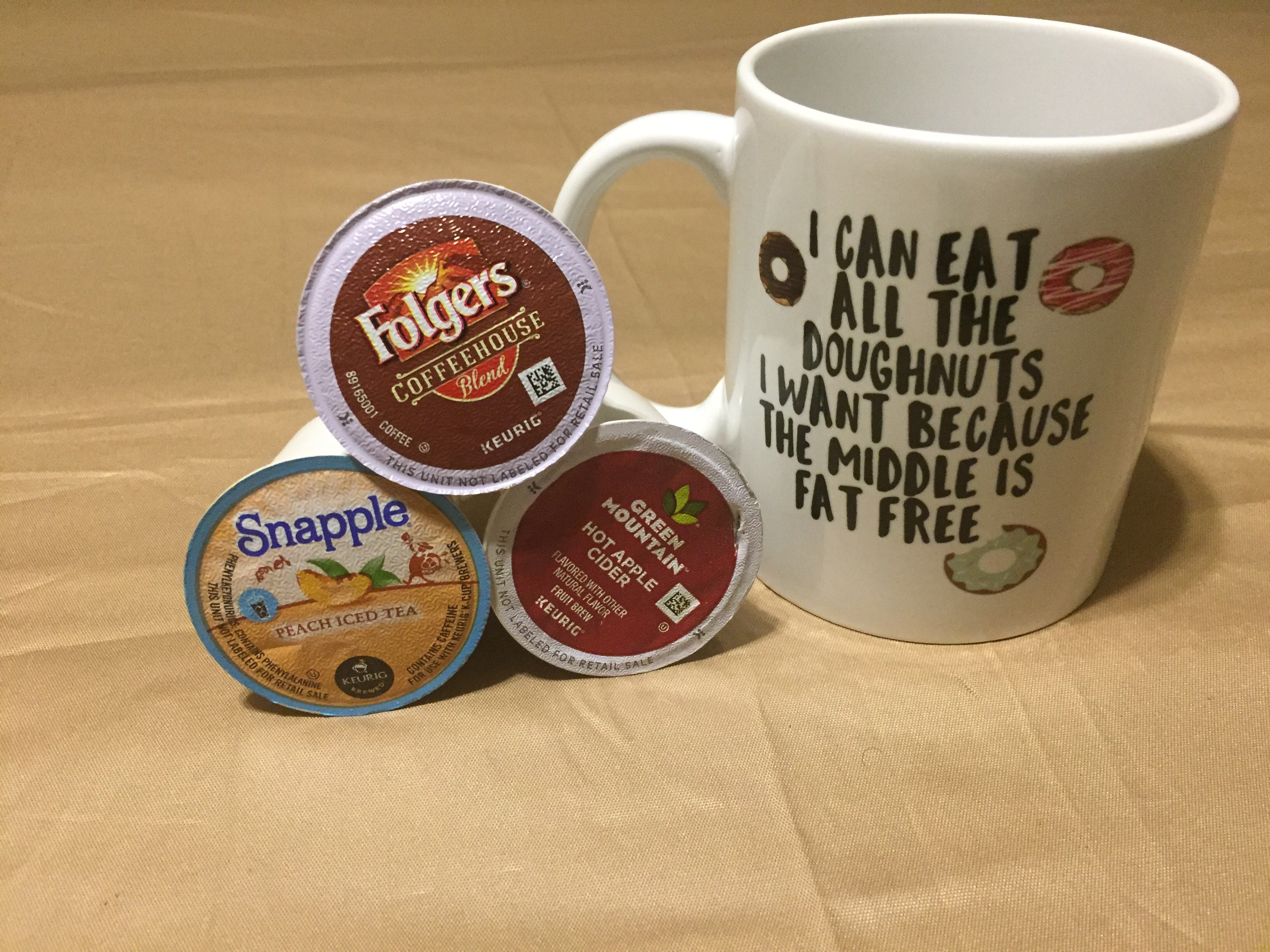 A glossy white ceramic mug with the phrase 'I Can Eat All The Doughnuts' printed on it, perfect for coffee or tea.