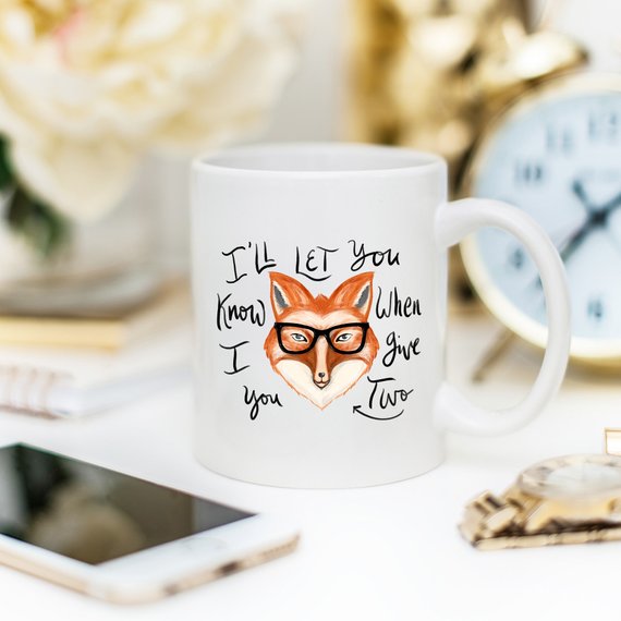 A humorous coffee mug featuring the phrase 'I'll Let You Know When I Give Two Fox', designed for coffee lovers.