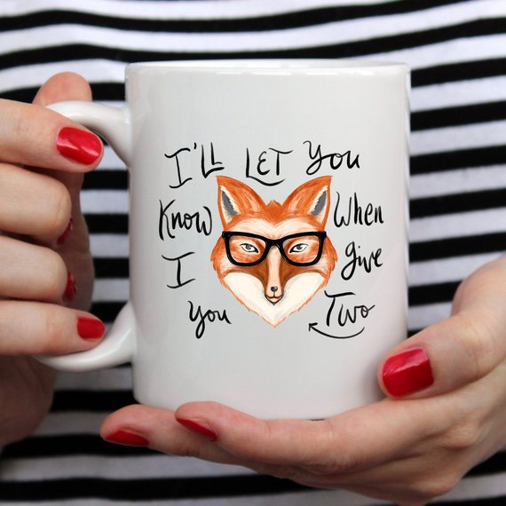 A humorous coffee mug featuring the phrase 'I'll Let You Know When I Give Two Fox', designed for coffee lovers.