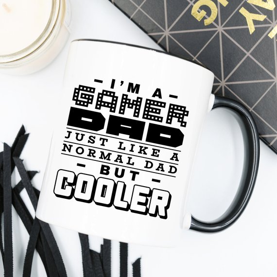 Funny coffee mug featuring the phrase 'I'm A Gamer Dad, Just Like A Normal Dad But Cooler', designed for gamer dads.