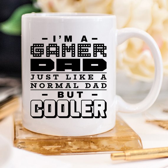 Funny coffee mug featuring the phrase 'I'm A Gamer Dad, Just Like A Normal Dad But Cooler', designed for gamer dads.