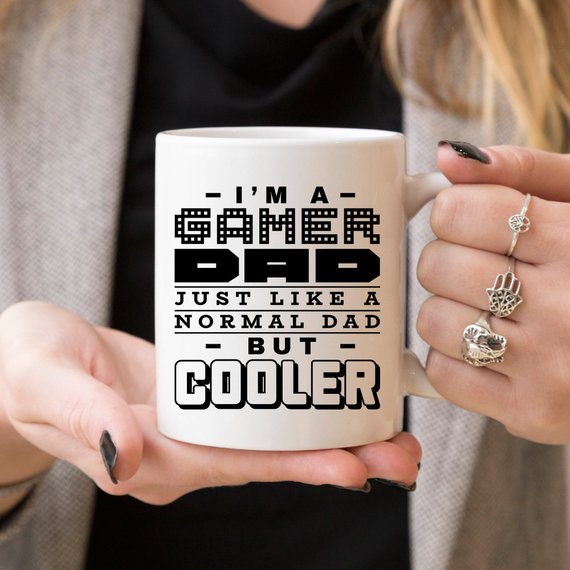 Funny coffee mug featuring the phrase 'I'm A Gamer Dad, Just Like A Normal Dad But Cooler', designed for gamer dads.