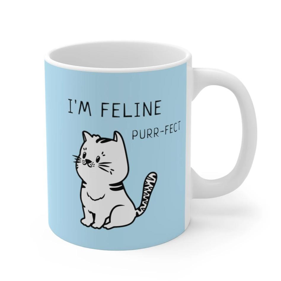 I'm Feline Purr-Fect Mug in Blue, featuring a charming cat design on a white ceramic body, perfect for coffee or tea.