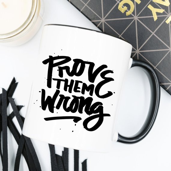 A white ceramic coffee mug with the phrase 'Prove Them Wrong' printed in bold letters, showcasing a motivational and humorous design.