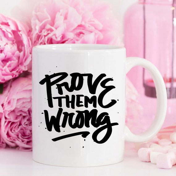 A white ceramic coffee mug with the phrase 'Prove Them Wrong' printed in bold letters, showcasing a motivational and humorous design.