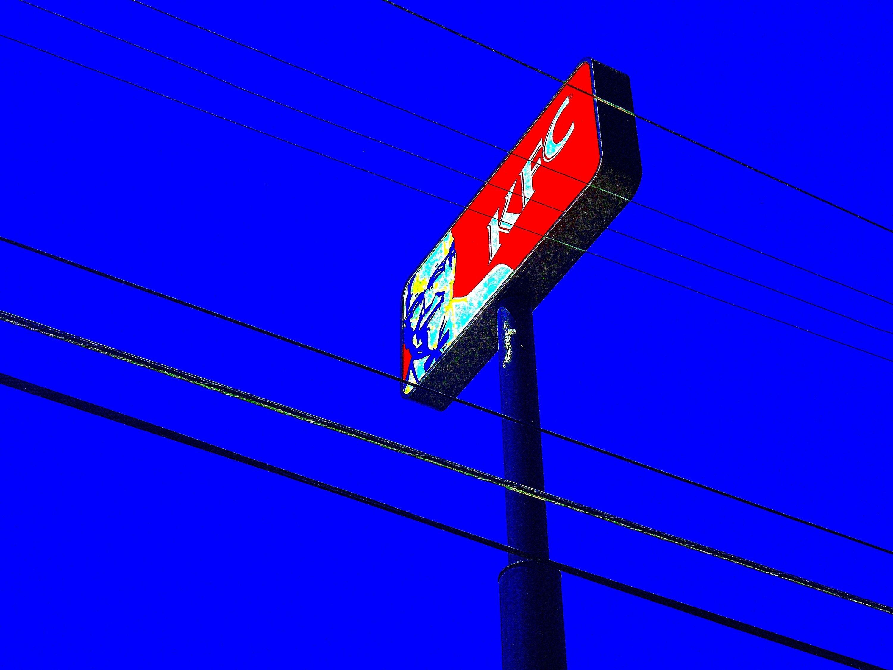 Colorful Kentucky Fried Chicken pop art print featuring the iconic logo against a bright blue sky.