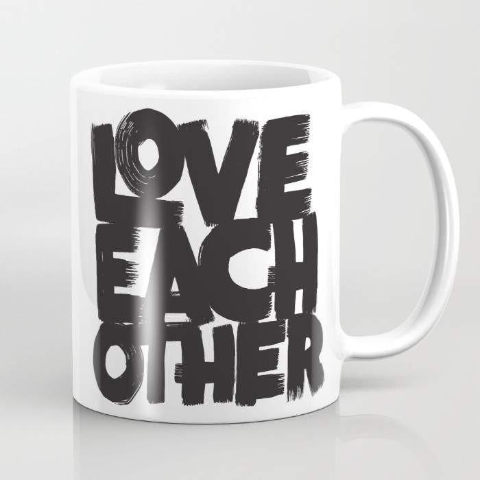 A stylish 15-ounce ceramic mug with a wrap-around design featuring the phrase 'Love Each Other', showcasing a large handle for easy gripping.