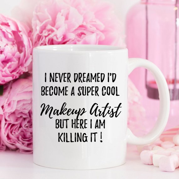 A stylish white ceramic mug designed for makeup artists, featuring vibrant designs on both sides, perfect for coffee or tea.