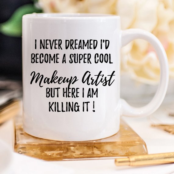 A stylish white ceramic mug designed for makeup artists, featuring vibrant designs on both sides, perfect for coffee or tea.