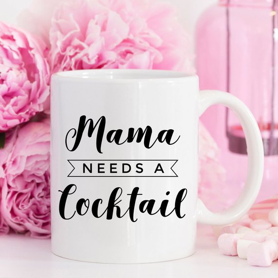 A humorous coffee mug with the text 'Mama Needs A Cocktail', showcasing a fun design perfect for Mother's Day gifts.