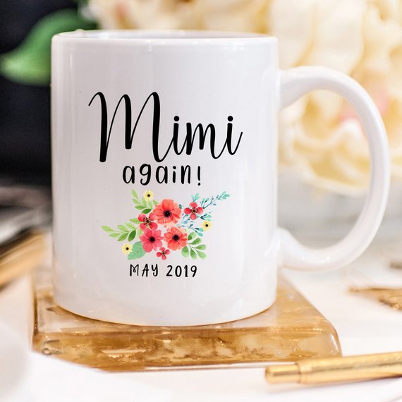 White ceramic mug with pregnancy announcement design printed on both sides, perfect for new moms.