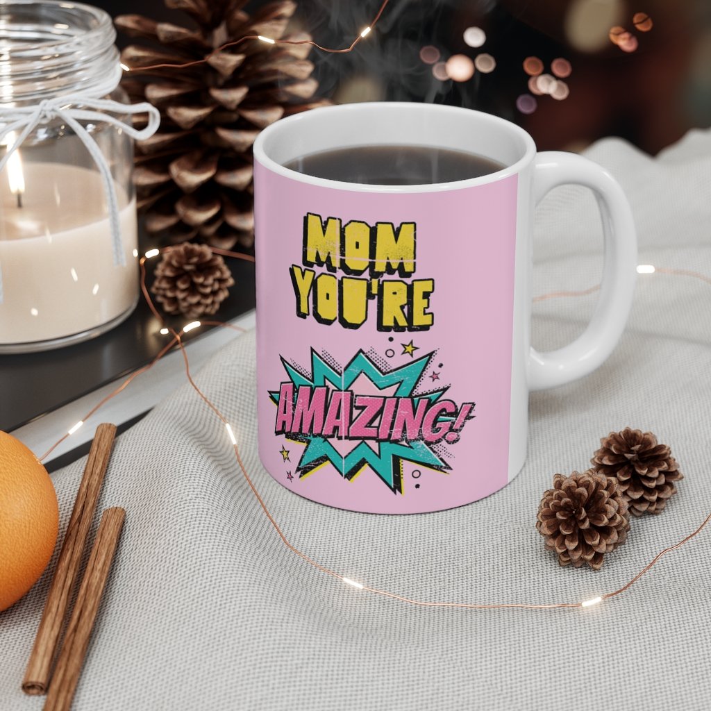 A white ceramic mug featuring a comic theme design with the text 'Mom You're Amazing' and a heartwarming message.