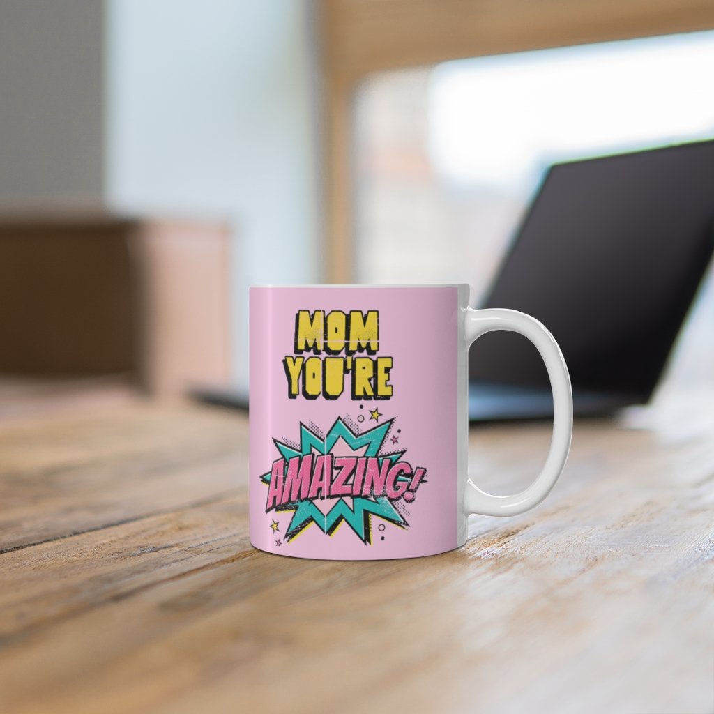 A white ceramic mug featuring a comic theme design with the text 'Mom You're Amazing' and a heartwarming message.