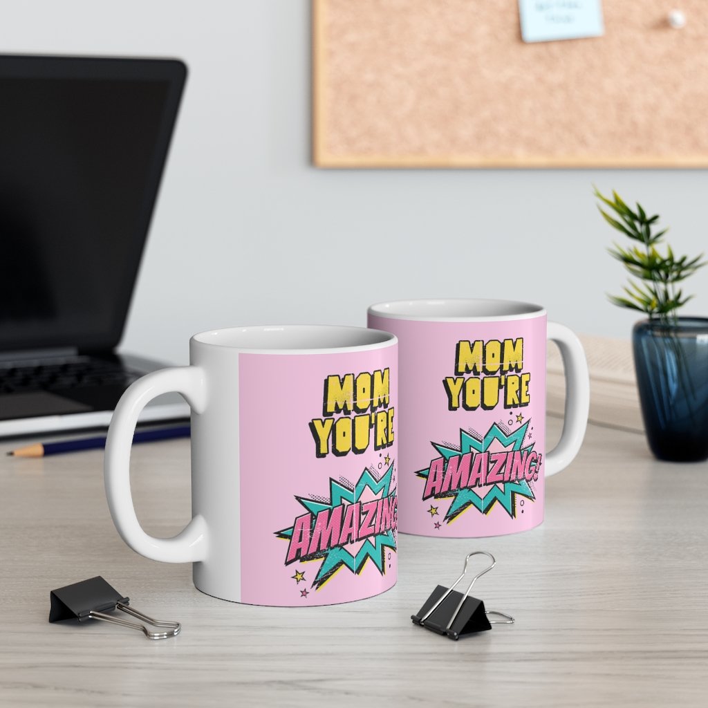 A white ceramic mug featuring a comic theme design with the text 'Mom You're Amazing' and a heartwarming message.