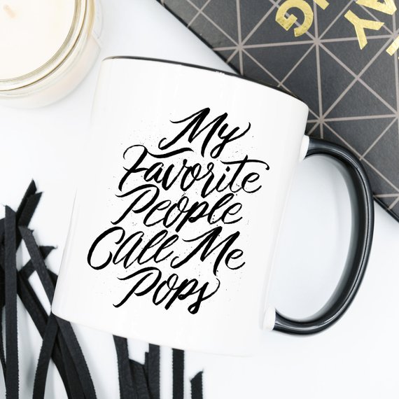 A white ceramic coffee mug with the text 'My Favorite People Call Me Pops' printed in a fun font, perfect for gifting.