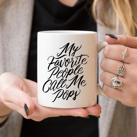 A white ceramic coffee mug with the text 'My Favorite People Call Me Pops' printed in a fun font, perfect for gifting.