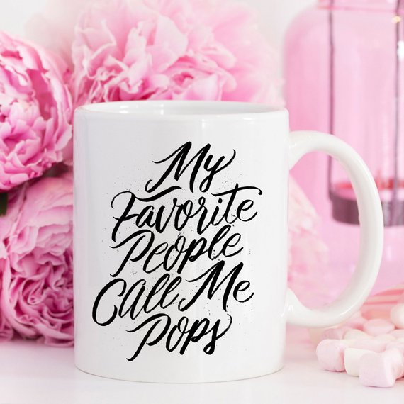 A white ceramic coffee mug with the text 'My Favorite People Call Me Pops' printed in a fun font, perfect for gifting.