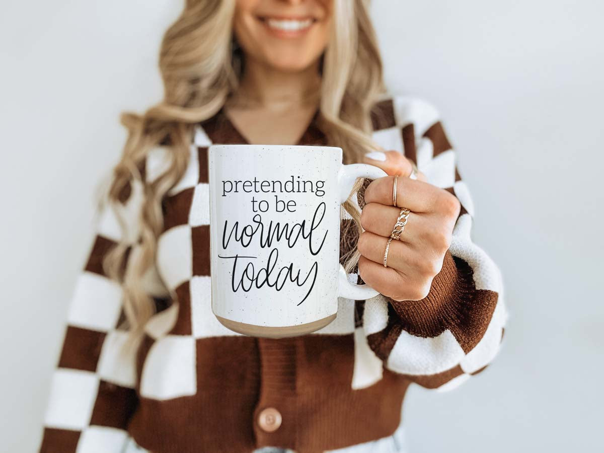 A 16oz off-white ceramic mug with dark speckles, featuring the humorous text 'Pretending to be Normal Today' on both sides.