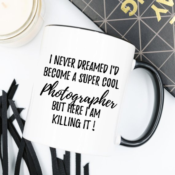 A white ceramic mug featuring a vibrant photography-themed design, showcasing a camera and photography elements, perfect for photographers.