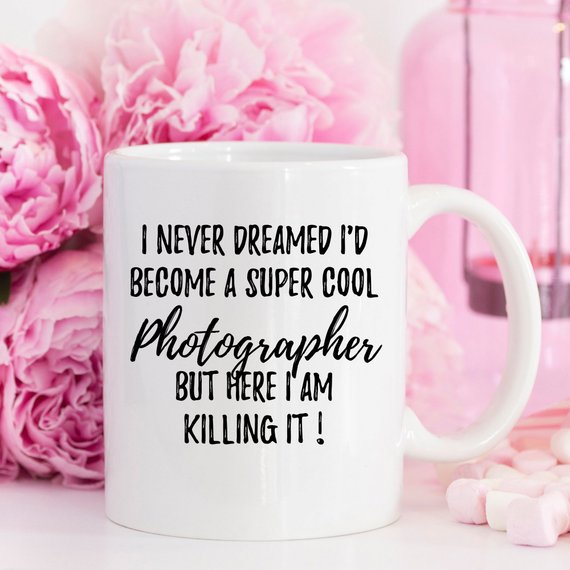 A white ceramic mug featuring a vibrant photography-themed design, showcasing a camera and photography elements, perfect for photographers.