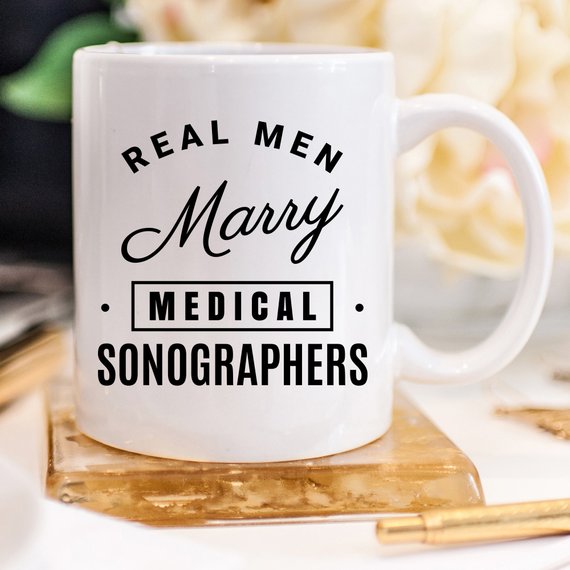 A humorous coffee mug featuring the phrase 'Real Men Marry Medical Sonographers', showcasing a fun design perfect for gifts.