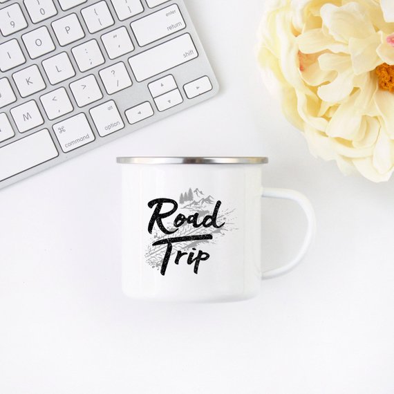 A white enamel camping mug with a stainless steel rim, featuring a vibrant road trip design printed on both sides, perfect for outdoor adventures.