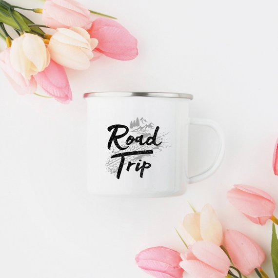 A white enamel camping mug with a stainless steel rim, featuring a vibrant road trip design printed on both sides, perfect for outdoor adventures.