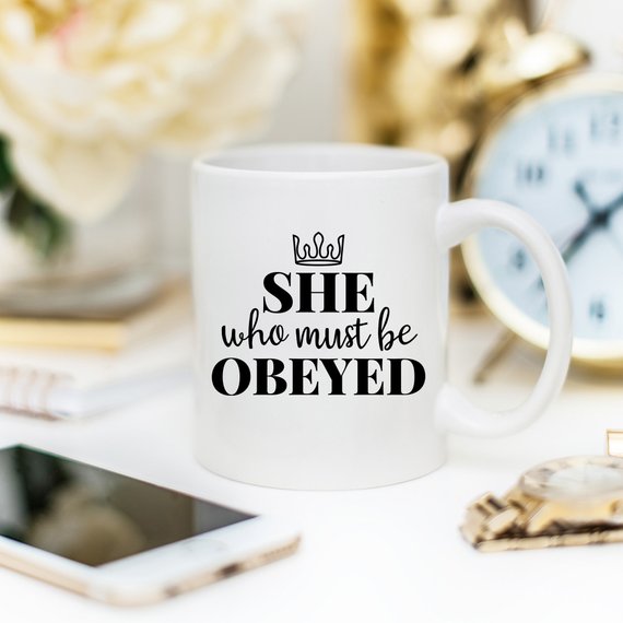 A humorous coffee mug with the phrase 'She Who Must Be Obeyed' printed on it, made from high-quality ceramic.