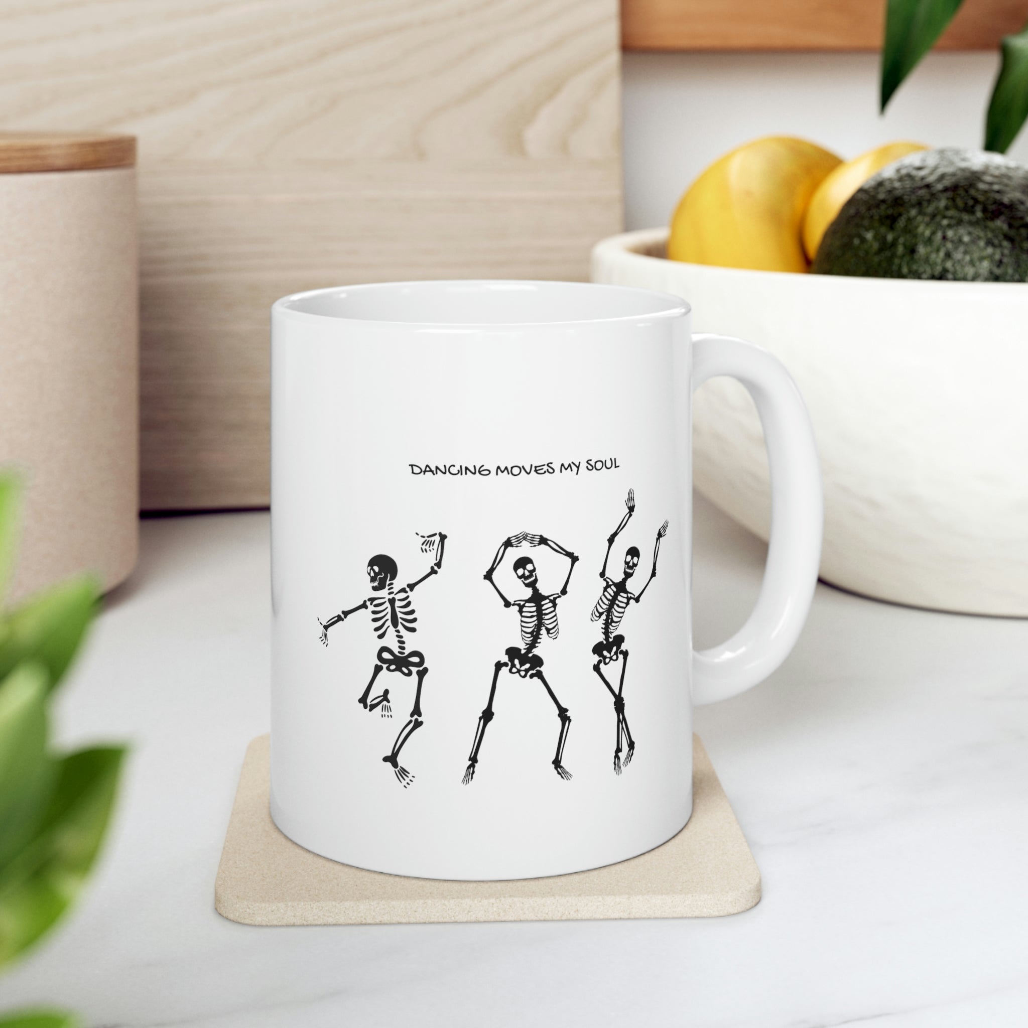 A white ceramic mug featuring a playful design of dancing skeletons, perfect for coffee and tea lovers.