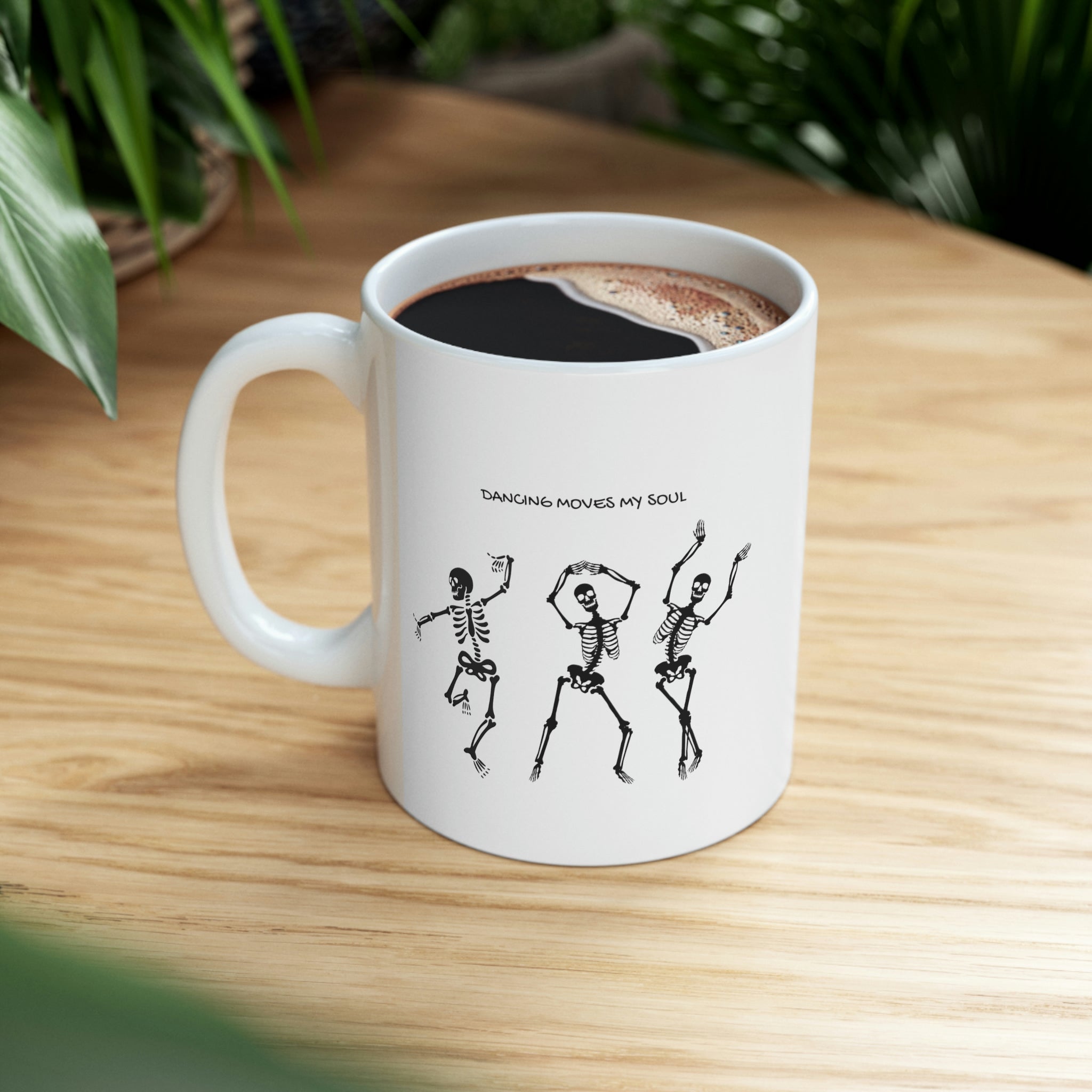 A white ceramic mug featuring a playful design of dancing skeletons, perfect for coffee and tea lovers.