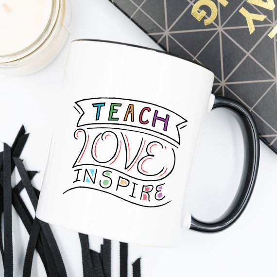 A ceramic coffee mug featuring the phrase 'Teach Love Inspire' in a fun design, perfect for teachers.