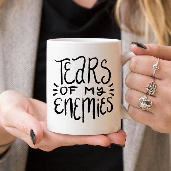 A humorous coffee mug with the phrase 'Tears Of My Enemies' printed on it, showcasing a fun design perfect for coffee lovers.