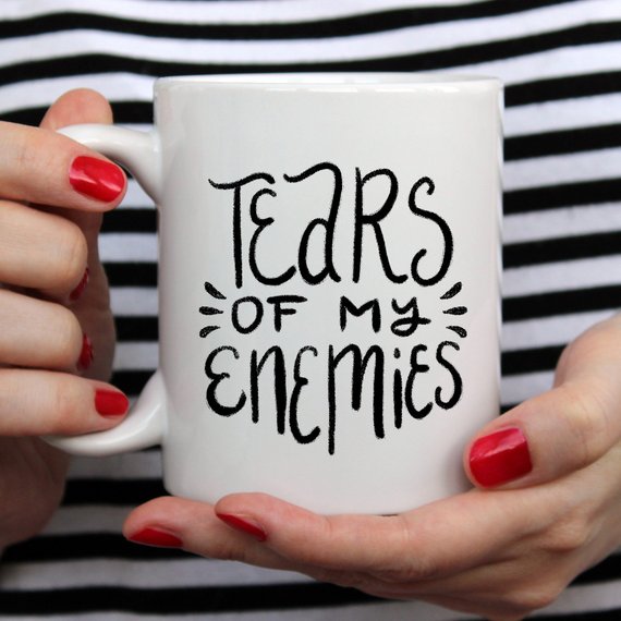 A humorous coffee mug with the phrase 'Tears Of My Enemies' printed on it, showcasing a fun design perfect for coffee lovers.