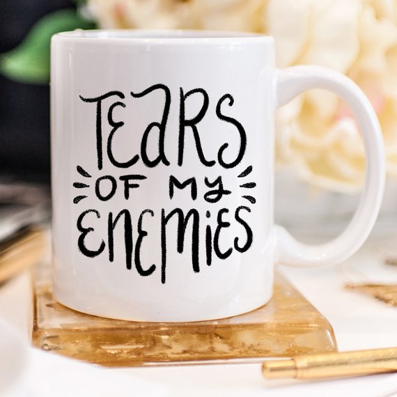 A humorous coffee mug with the phrase 'Tears Of My Enemies' printed on it, showcasing a fun design perfect for coffee lovers.