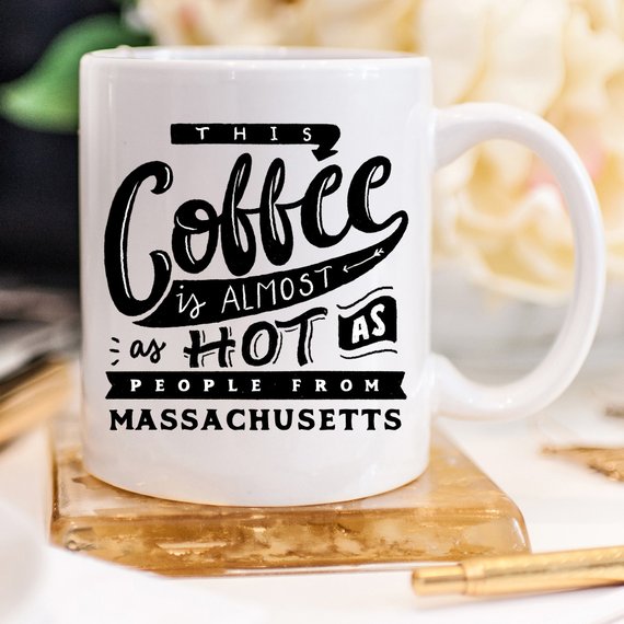 Funny coffee mug with the phrase 'This Coffee Is Almost As Hot As People From Massachusetts' printed on it, showcasing a humorous design.