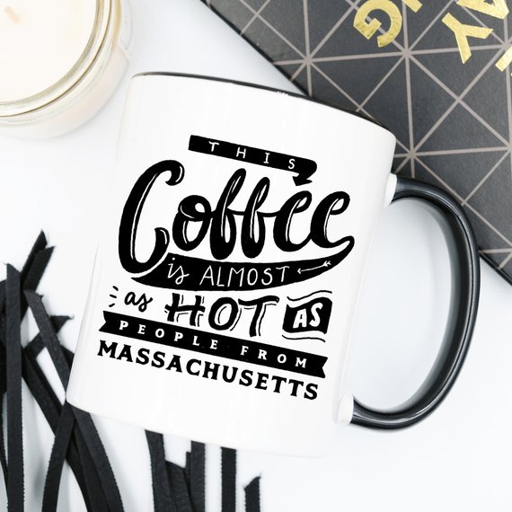 Funny coffee mug with the phrase 'This Coffee Is Almost As Hot As People From Massachusetts' printed on it, showcasing a humorous design.