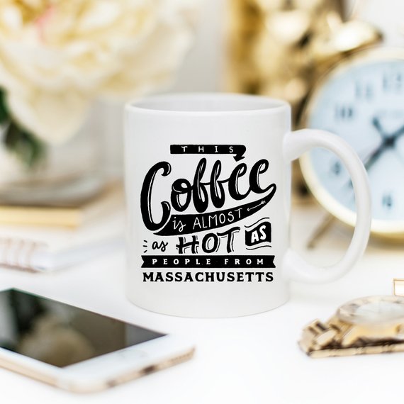 Funny coffee mug with the phrase 'This Coffee Is Almost As Hot As People From Massachusetts' printed on it, showcasing a humorous design.