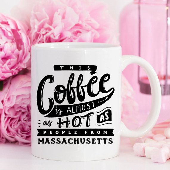 Funny coffee mug with the phrase 'This Coffee Is Almost As Hot As People From Massachusetts' printed on it, showcasing a humorous design.