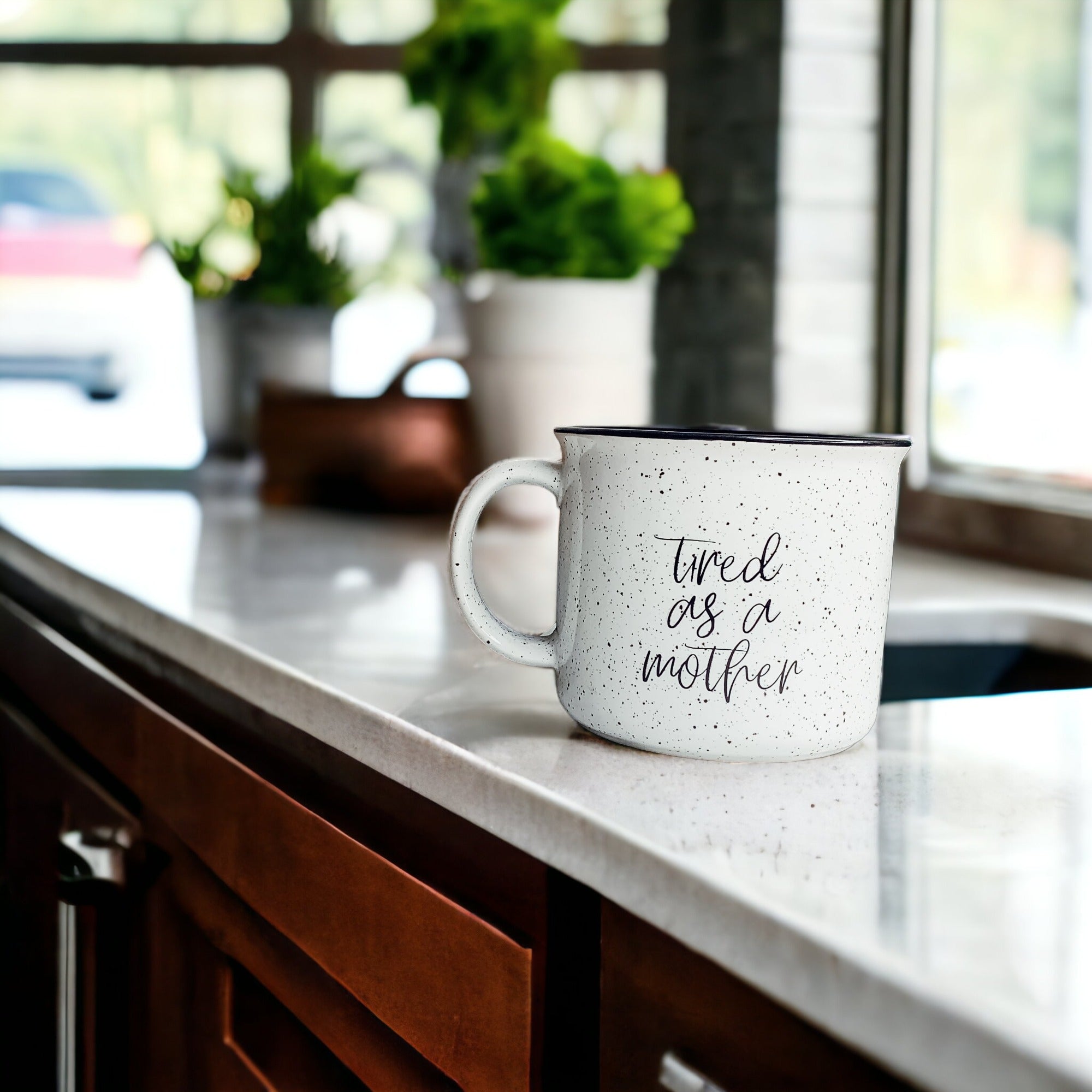 Tired as a Mother Campfire Mug with black rim and double-sided design, featuring white sesame glaze and bold black lettering.