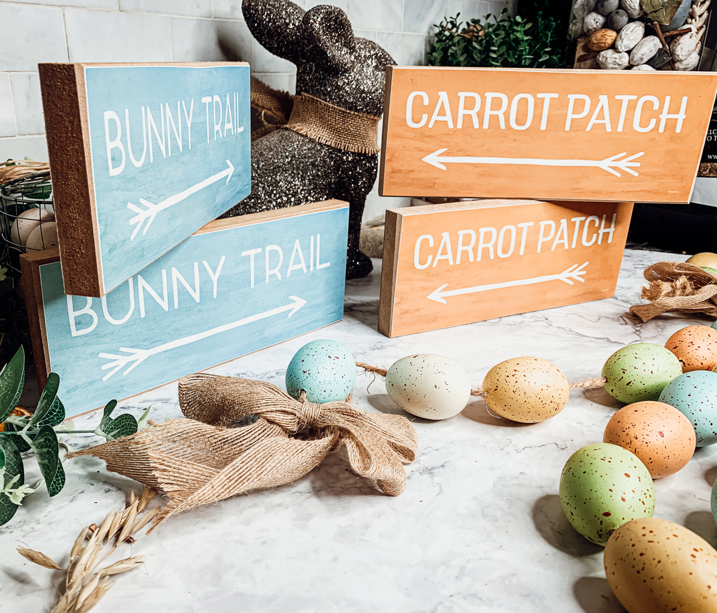 Two wooden block signs featuring Bunny Trail and Carrot Patch designs in pastel colors, perfect for Easter decor.