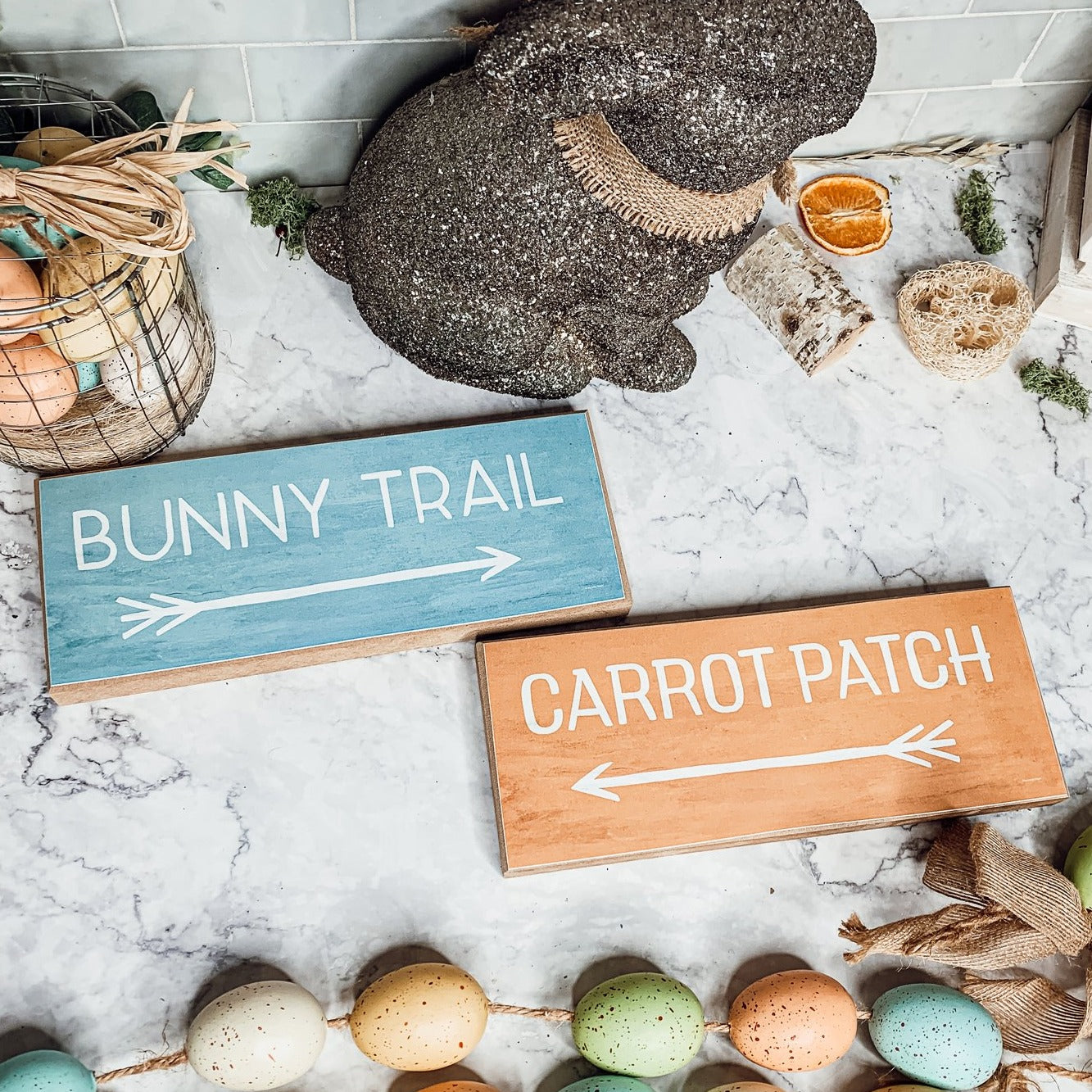 Two wooden block signs featuring Bunny Trail and Carrot Patch designs in pastel colors, perfect for Easter decor.