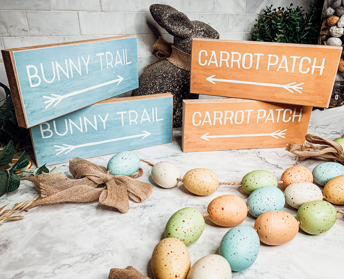 Two wooden block signs featuring Bunny Trail and Carrot Patch designs in pastel colors, perfect for Easter decor.