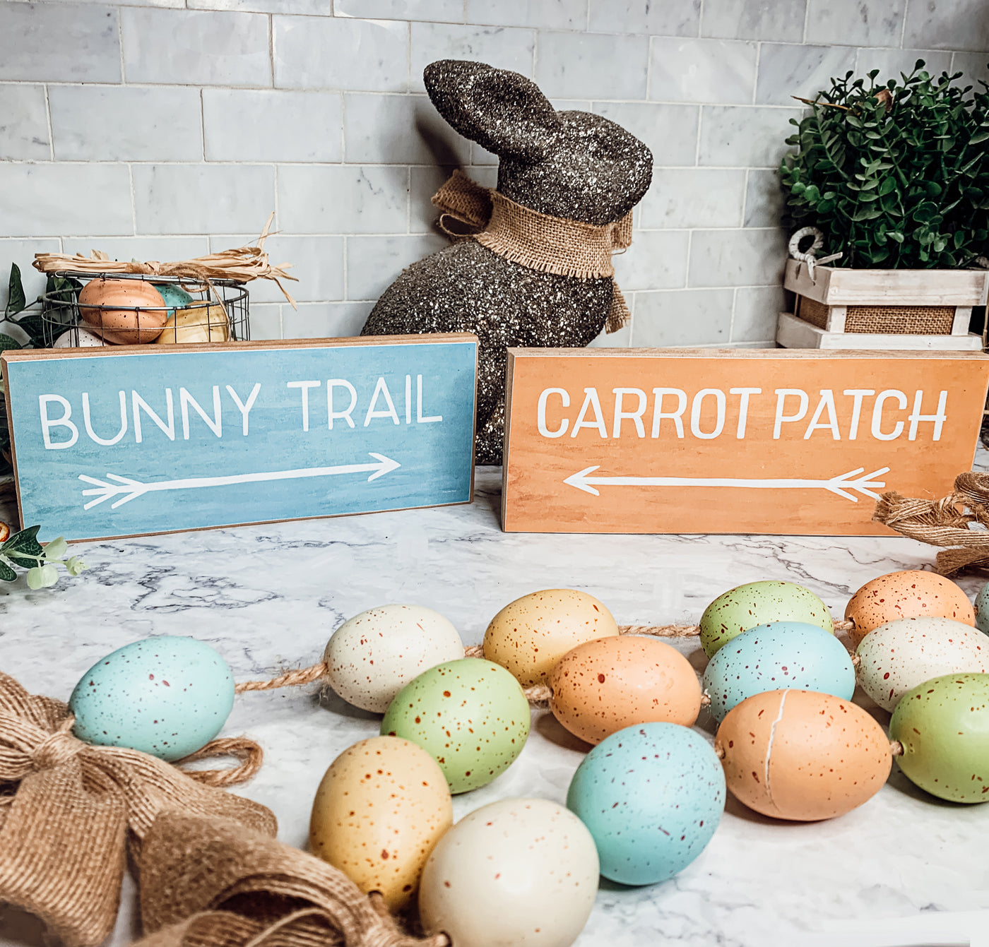 Two wooden block signs featuring Bunny Trail and Carrot Patch designs in pastel colors, perfect for Easter decor.