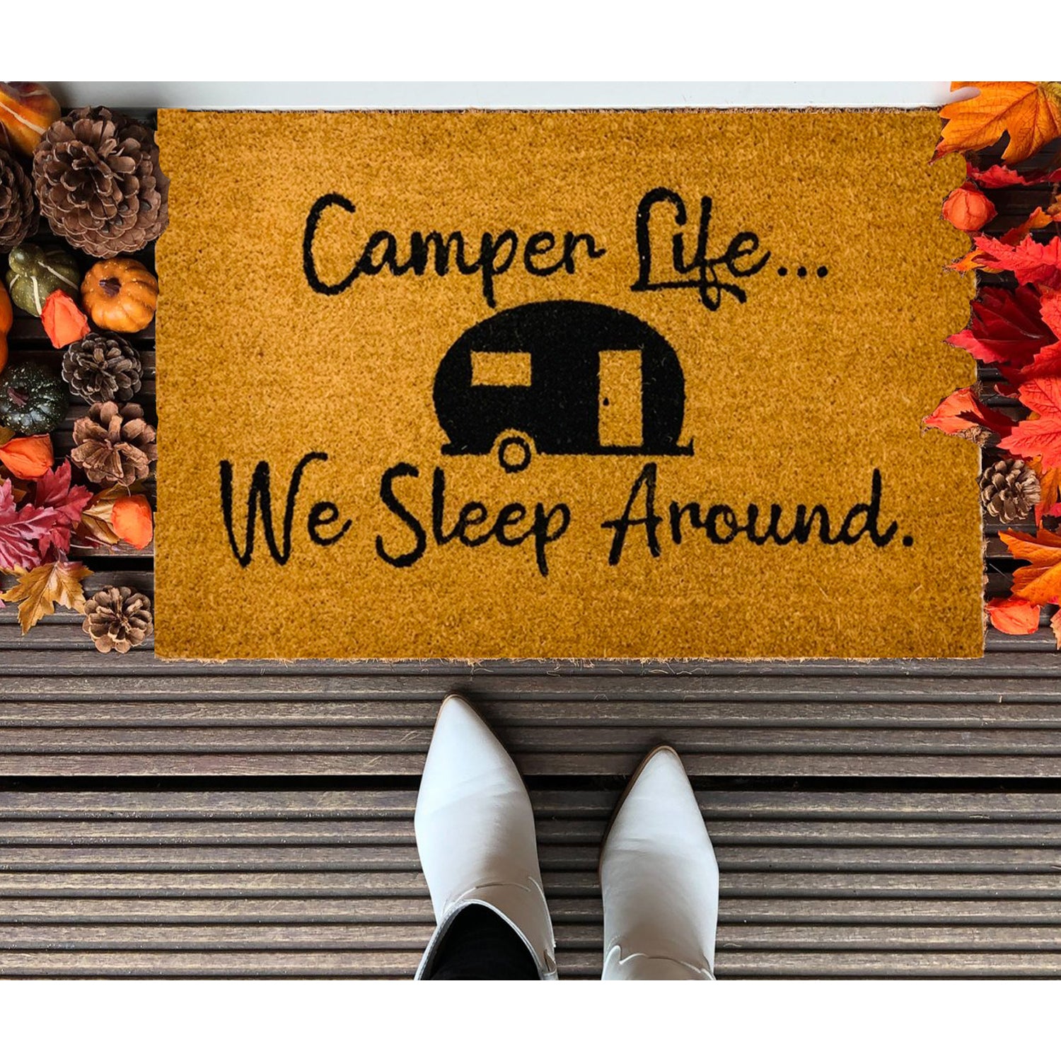 A humorous doormat with the phrase 'We Sleep Around', made of coir, perfect for camping entrances.