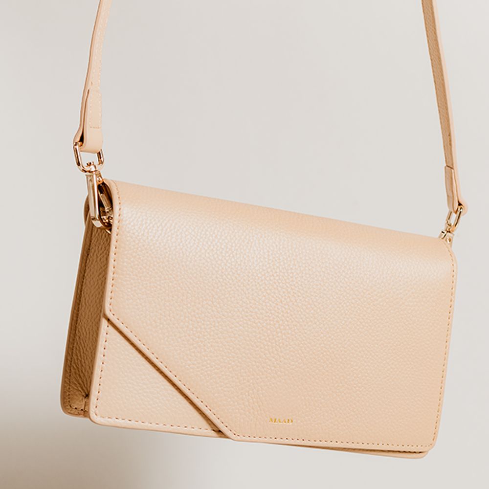 Match Sandy Nude Asymmetric Crossbody bag featuring smooth pebble leather and suede lining, with an adjustable strap and interior pocket.