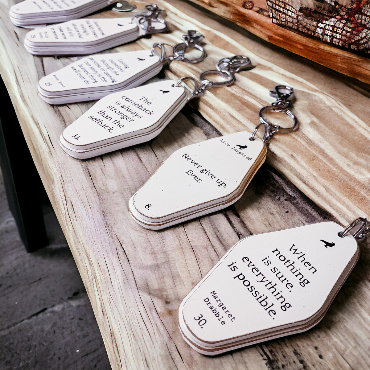 A collection of wooden key chains featuring various inspirational quotes, showcasing their durable design and stylish black and white colors.