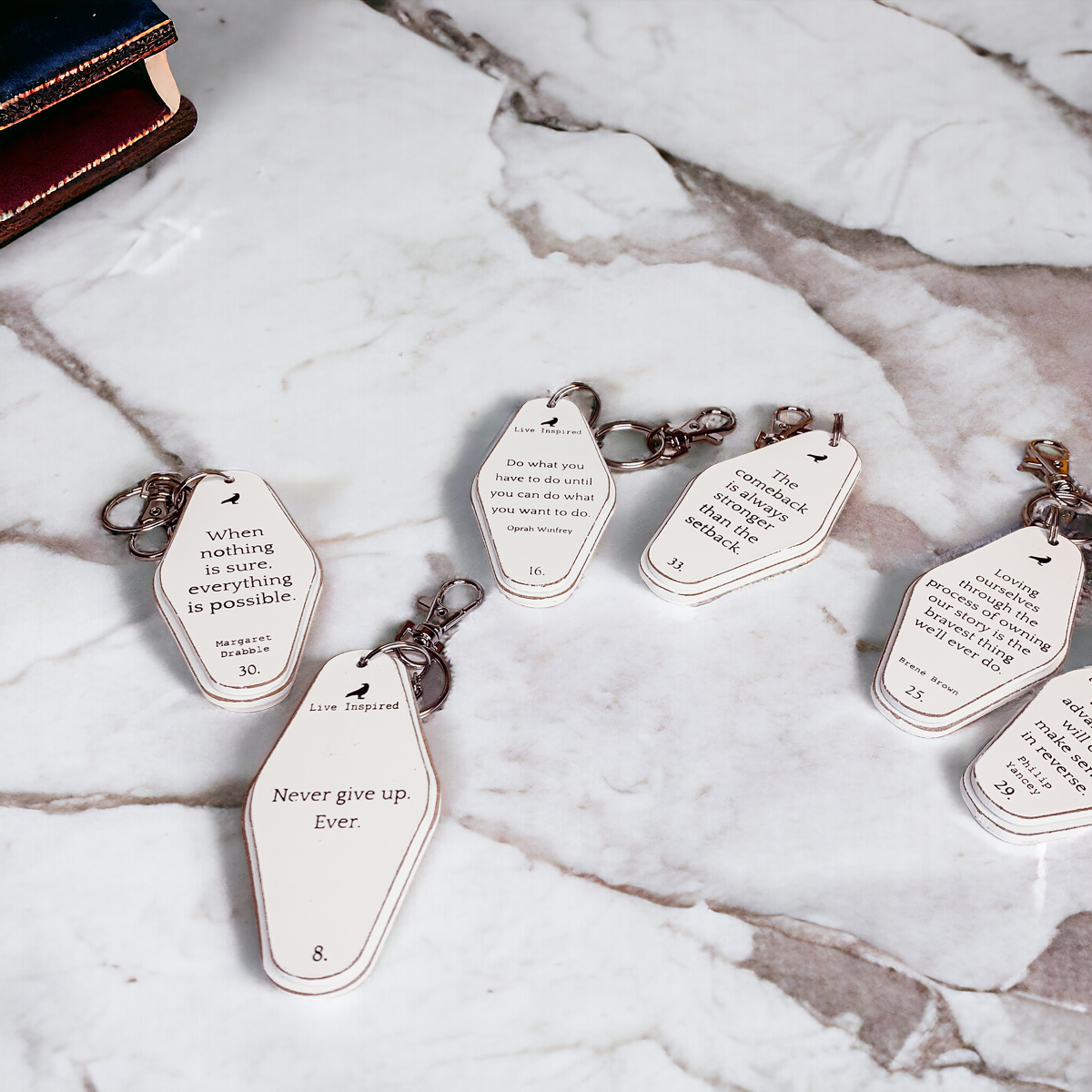 A collection of wooden key chains featuring various inspirational quotes, showcasing their durable design and stylish black and white colors.